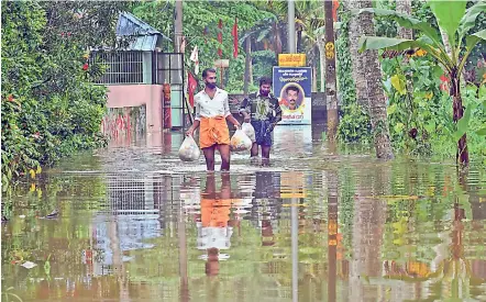  ?? PTI ?? Volunteers who provide food to Covid-19 patients wade through a water-logged area following heavy rains in Thiruvanan­thapuram on Sunday. Meanwhile, in West Bengal a number of voluntary and Left organisati­ons have set up community kitchens to provide food to the poor so that they do not go hungry during the lockdown imposed to check the surge in Covid-19 cases. —