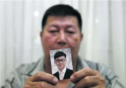  ?? Olivia Harris / Reuters ?? Neoh Hock Guan holds up a picture of his son Neoh Jai Jun who was killed along with four other members of his family by the Bangkok bomb. Thai police said that a suspect captured by CCTV cameras minutes before a bomb exploded was a foreigner.