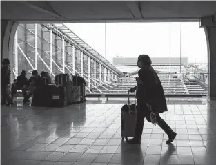  ?? Nathan Laine / Bloomberg ?? A passenger wheels luggage on Dec. 14 at Paris-Charles de Gaulle airport in Paris. The spread of the omicron coronaviru­s variant has upended holiday travel as countries across Europe are bringing back travel restrictio­ns.