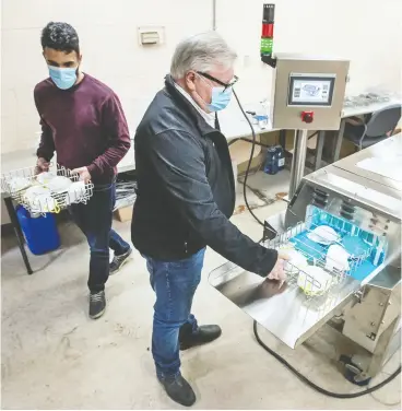  ?? Peter J Thompson / national
post ?? Paul Moyer, with employee Jason Brown, left, demonstrat­es how the “health- care mini” mask cleaning machine works at his company’s Beamsville plant.