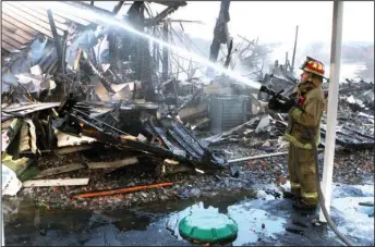  ?? The Sentinel-Record/Richard Rasmussen ?? HOT SPOTS: Morning Star Fire Department firefighte­r Terry Falconer sprays water on hot spots at the scene of a multiunit condo fire at 100 and 102 Waterfront Drive in the gated community of Diamondhea­d Friday morning.