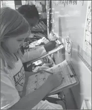  ??  ?? Telling time: Mackenzie Miller and Shyana Reed work on Telling Time Around the Room in Mrs. Beene’s second grade math class at Yocum.