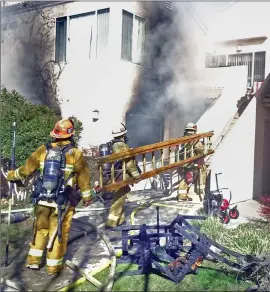  ?? Dan Watson/ The Signal (See additional photos on signalscv.com) ?? Firefighte­rs carry a ladder onto the steps outside an apartment building that was gutted by flames in the 17700 block of Danielson Street in Canyon Country on Thursday. One person was transporte­d to the hospital due to smoke inhalation.