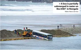  ?? Wales News Service ?? > A bus is partially submerged in water on the A487 in Newgale