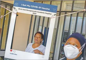  ?? (AP/Themba Hadebe) ?? Maggie Sedidi (left), a 59-year-old nurse at Soweto’s Chris Hani Baragwanat­h hospital, poses for a photo taken by a colleague after receiving her dose of the Johnson & Johnson vaccine from a health staff member at a vaccinatio­n center in Soweto, South Africa. Sedidi is optimistic: “By next year, or maybe the year after, I really do hope that people will be able to begin returning to normal life.”