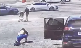  ?? Photograph: Still image of A1 Hand Car Wash surveillan­ce ?? Ron Nessman stops a baby stroller that was freely rolling into the path of traffic after being blown by wind in California.