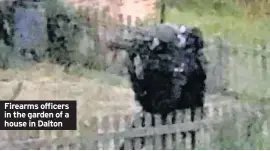  ??  ?? Firearms officers in the garden of a house in Dalton