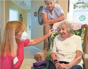  ?? JON AUSTRIA/USA TODAY NETWORK ?? Registered nurse Joanne Freeborn, left, checks the temperatur­e of Mary Jo Smith’s mother, Jean Murphy, in October at their home in East Naples, Fla.