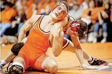  ?? [PHOTO BY IAN MAULE, TULSA WORLD] ?? Oklahoma State’s Dean Heil, front, attempts to escape Oklahoma’s Mike Longo during Sunday’s Bedlam wrestling dual at Gallagher-Iba Arena. Heil won his 32nd-straight match, beating Longo, 5-3.