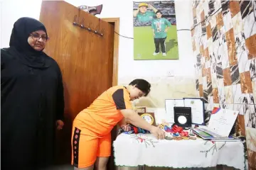  ??  ?? Iraqi badminton player Heba Asghar arranges her medals at her home in Baghdad next to her mother in this on July 8 file photo.