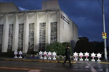  ?? AP PHOTO/GENE J. PUSKAR, FILE ?? A Pittsburgh Police officer walks past the Tree of Life Synagogue and a memorial of flowers and stars in Pittsburgh in remembranc­e of those killed and injured when a shooter opened fire during services Saturday at the synagogue. The social media site popular with farright extremists and apparently used by the Pittsburgh synagogue shooting suspect, advertises as a haven for free-speech fans. As more mainstream sites have cracked down on hate speech and threats of violence, critics say Gab has become a breeding ground for white nationalis­ts, neo-Nazis and other extremists.