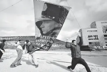  ?? AP ?? A portrait of Russian leader Vladimir Putin is attached to a balloon Thursday in Sevastopol, Crimea, on the seventh anniversar­y of the annexation from Ukraine. The sign reads: “Another gave us back the cradle of baptism. March 18, 2014.” Meanwhile, the Group of Seven major industrial­ized countries condemned what it called Russia’s ongoing “occupation” of the peninsula.