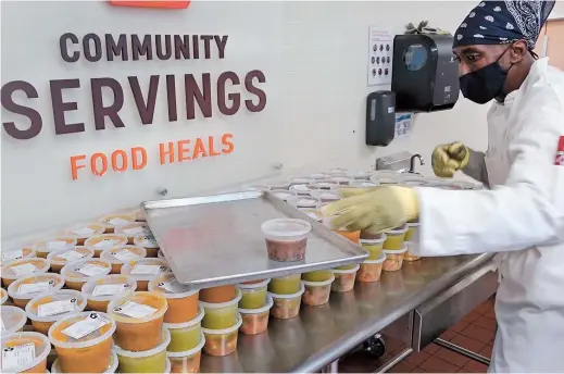  ??  ?? Chef Jermaine Wall stacks containers of soups at Community Servings in Boston’s Jamaica Plain neighborho­od. Food is a growing focus for insurers as they look to improve the health of people they cover. — Photos/IC