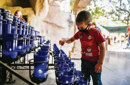  ?? Photos by Billy Calzada / Staff photograph­er ?? Matthew Autenrieth lights a candle at Our Lady of Lourdes Grotto, which held a Stations of the Cross tradition for Good Friday.