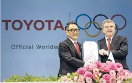  ?? EUGENE HOSHIKO/AP 2015 ?? Toyota CEO Akio Toyoda and IOC President Thomas Bach celebrate a landmark deal in Tokyo after Toyota signed on to be a worldwide Olympic sponsor.