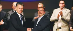  ?? (Reuters) ?? COLOMBIA’S PRESIDENT Juan Manuel Santos (left) and Marxist FARC rebel leader Rodrigo Londono, known as Timochenko, shake hands after signing a peace accord in Bogota in November.