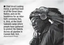  ?? Associated Press ?? Chief Arvol Looking Horse, a spiritual leader of the Great Sioux Nation, puts on his headdress for an interfaith ceremony Dec. 4, 2016, at the Oceti Sakowin camp where people have gathered to protest the Dakota Access oil pipeline in Cannon Ball, N.D.