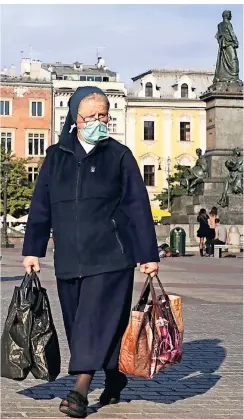  ?? FOTO: BEATA ZAWRZEL/DPA ?? Eine Nonne geht mit Mundschutz über den historisch­en Hauptmarkt von Krakau im Süden Polens.