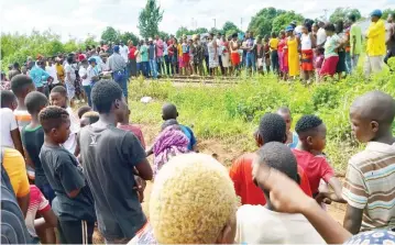  ?? ?? Residents of Chipadze suburb in Bindura gather to see the body of an unidentifi­ed man along the railway line to Shamva yesterday