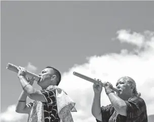  ?? DAEJA FALLAS/THE NEW YORK TIMES ?? Cody Pueo Pata and Lori Lei Ishikawa blow into pu ‘ohe, or hollowed-out bamboo pipes, Tuesday during a traditiona­l Hawaiian ceremony called a hula on the island of Maui. After Hawaii’s deadliest fires in more than a century, traditiona­l ceremonies are addressing spiritual healing.