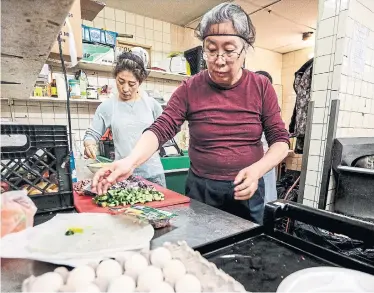  ?? ANDREW FRANCIS WALLACE TORONTO STAR ?? Annie, left, and Ying prepare lunch for clients of the Fort York Food Bank on College Street. The food bank serves more than 1,000 unique clients a month, some of whom will receive a special gift box at Christmas.