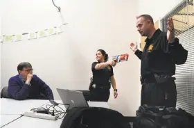  ?? Carlos Avila Gonzalez / The Chronicle ?? UC Berkeley police Sgt. Sabrina Reich holds a toy gun while playing the role of the shooter as Cpl. Wade MacAdam reacts at a UC Berkeley training session.