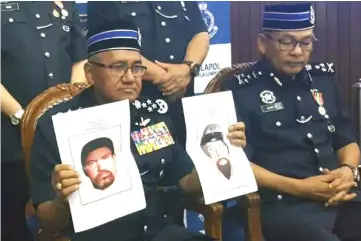  ??  ?? Fuzi (left) holding up photo-fit of the suspects in the murder of Fadi. — Bernama photo