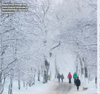  ?? OUTJAN WOITAS ?? People stroll through the snow-covered landscape in Oberwiesen­thal, Germany