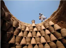  ??  ?? A clay pot is placed with others at a makeshift factory in Peshawar. Pakistan’s competitiv­eness ranking has improved