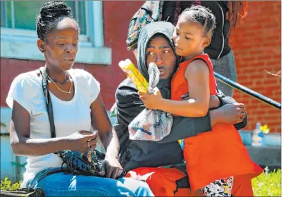  ?? Robert Cohen The Associated Press ?? Devation Powell, the father of slain 3-year-old Kennedi Powell, hugs his cousin Shylar Roberts, 5, on Monday as he sits near where Kennedi was shot the night before along Michigan Avenue in St. Louis. Sharonda Edmondson, Kennedi’s great-aunt, is at left.