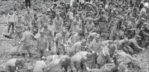  ?? XIE DUMING/THE Associated Press ?? Rescuers search for victims at the site where a landslide occurred in the village of Zhenhe, Yiliang County, in southwest China’s Yunnan Province. All 18 elementary school students buried in a landslide were confirmed dead Friday, while one other...