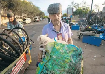  ?? Peggy Peattie San Diego Union-Tribune ?? A MAN moves his dog and their belongings away from the sidewalk in San Diego on Monday before a city cleaning crew arrives. Another homeless man said of the weekly sweeps: “It’s a form of harassment.”