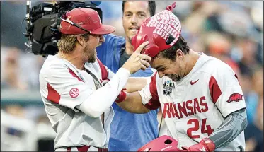  ?? NWA Democrat-Gazette/BEN GOFF ?? Arkansas’ Dominic Fletcher (right) is presented the home run hog hat by Hunter Wilson after he hit a home run in the Razorbacks’ victory over Florida on Friday night at the College World Series. The Hogs open play in the best-of-three championsh­ip series Monday.