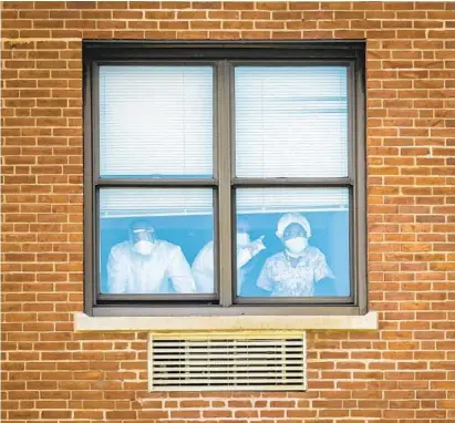  ?? JERRY JACKSON/BALTIMORE SUN ?? People look out the window at FutureCare Lochearn after officials said they uncovered an outbreak of COVID-19 among its population of 200 residents. The facility conducted widespread testing of both symptomati­c and asymptomat­ic residents and staff.