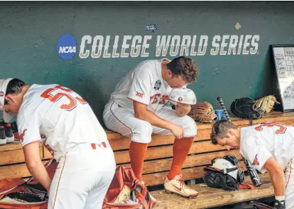  ?? Nati Harnik / Associated Press ?? Texas pitcher Andy McGuire sits in the dugout between Turner Gauntt (right) and Sam Bertelson (left) following the Longhorns’ 6-1 eliminatio­n game loss to defending national champion Florida on Tuesday.