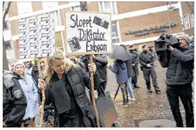  ?? HENNING KAISER /DPA ?? A woman holds up signs against Turkish President Erdogan near Hotel Senatshote­l in Cologne, Germany, on Sunday. The Turkish minister of economic affairs, Nihat Zeybekci, was to speak there Sunday evening.