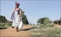  ??  ?? DAILY ROUND: A woman pushes firewood in a wheelbarro­w and another wears traditiona­l dress in Mtititi Village in Giyani, Limpopo.