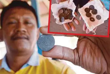  ??  ?? NORADIRA menunjukka­n syiling lama yang dijumpai di Pantai Mengabang Telipot.