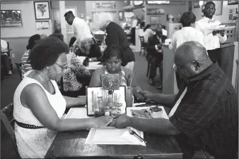  ?? THE WASHINGTON POST/TY WRIGHT ?? Terri Smith (left) — an evangelist at Genesis of Good Samaritans Ministries — holds hands with her husband Leroy Smith and her granddaugh­ter Yolanda Johnson as they say grace before eating lunch at the Family Affair Cafe &amp; Catering Co. in Groveport, Ohio. A poll by The Washington Post and the Kaiser Family Foundation found that about half of all Americans take a minute to say prayers over their food at least a few times a week; the poll reveals, making grace an unusual commonalit­y in a politicall­y divided nation.