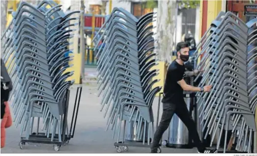  ?? JUAN CARLOS MUÑOZ ?? Un camarero recoge las sillas de una terraza en Sevilla en el horario de cierre de las tardes.