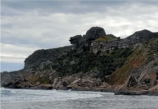  ?? GERARD HINDMARSH ?? The towering limestone monolith of Camel Rock dominates Turtle Beach and protects the luxuriant nikau forest behind.