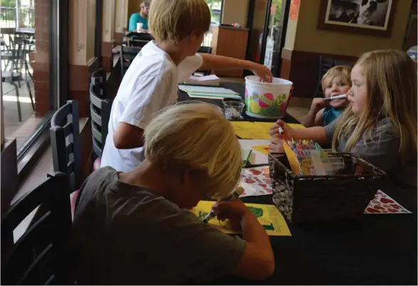  ?? (Photo by Sarah Raines, SDN) ?? Chick-fil-A provided craft supplies for children to create Father's Day cards on Saturday during its Dad's Day Off event. (Left front to back) Reeves Schiller, 4, and James Schiller, 10, from Starkville decorate cards sitting across the table from...