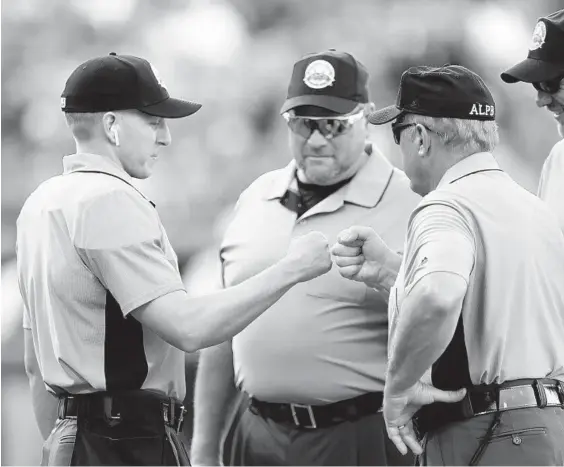  ?? JULIO CORTEZ/AP ?? Home plate ump Brian deBrauwere, left, wears an earpiece connected to a ball and strikes calling system before the start of the Atlantic League All-Star Game on Wednesday.