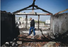  ?? (Amir Cohen/Reuters) ?? A MAN EXAMINES a home damaged by the wave of fires that hit the country last month, in Haifa on November 25.