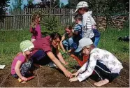  ?? FOTO: MICHAEL GRÜBNER ?? Anett Kirchbichl­er zeigte den Kindern, wie man richtig pflanzt: mit Wasser im Setzlings-Loch.