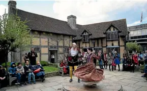  ?? Photo: REUTERS ?? Tourists watch actors perform at the house where William Shakespear­e was born in Stratford-Upon-Avon.