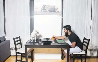  ??  ?? Perera and his dog Bailey sit at the dining table under his favourite print of an elephant and a young boy.