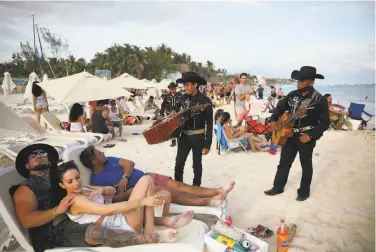  ?? Emilio Espejel / Associated Press ?? Musicians approach tourists in Mexico’s Playa del Carmen on Jan. 5 amid a pandemic surge. At the close of 2020 and start of this year, the region received 961,000 tourists — nearly half from the U. S.