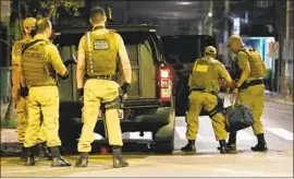  ?? Guilherme Hahn Futura Press ?? MILITARY POLICE carry a bag containing money left behind in the bank heist in Criciuma, Brazil. Authoritie­s said the robbers traded gunfire with off icers.