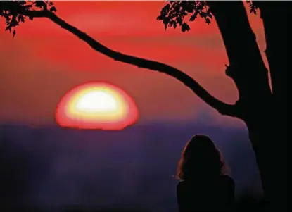  ?? Charlie Riedel / Associated Press ?? A woman watches the sun set July 3 from a park in Kansas City, Mo. For many in the U.S. and around the globe, thoughts now focus on 2021 — the year when everything, and maybe nothing, happens.